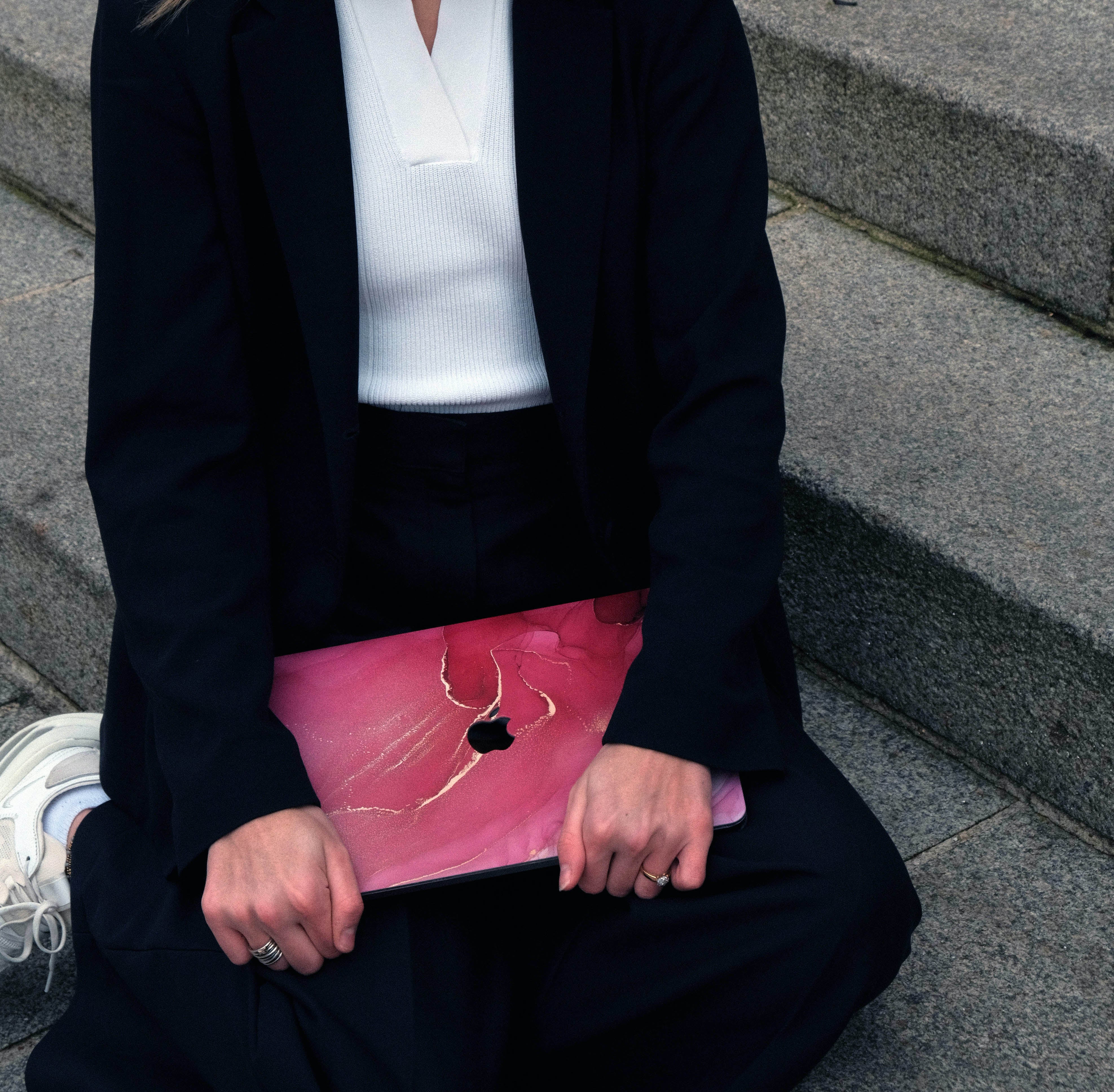 jeune femme assises bien habillée avec une coque macbook rouge vif dans ses mains
